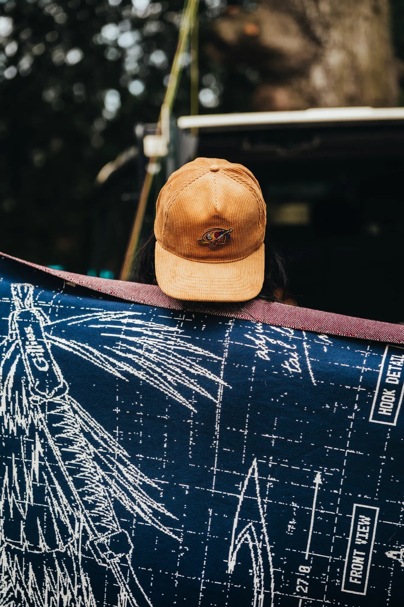 Tan corduroy cap resting on a blueprint fly-fishing blanket